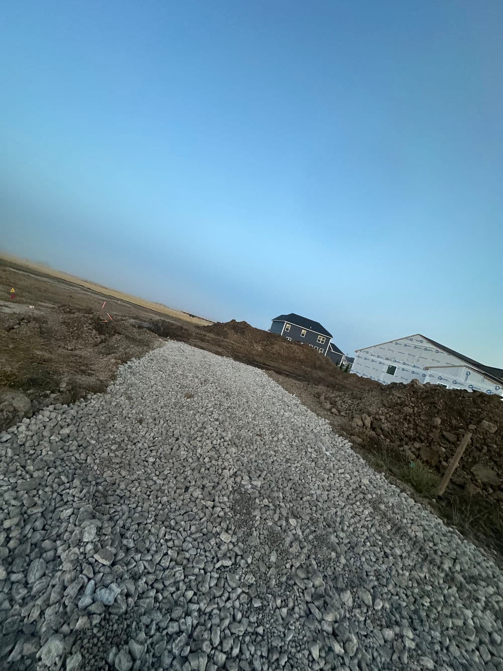 Gravel pathway in a construction site with house foundations in the background.