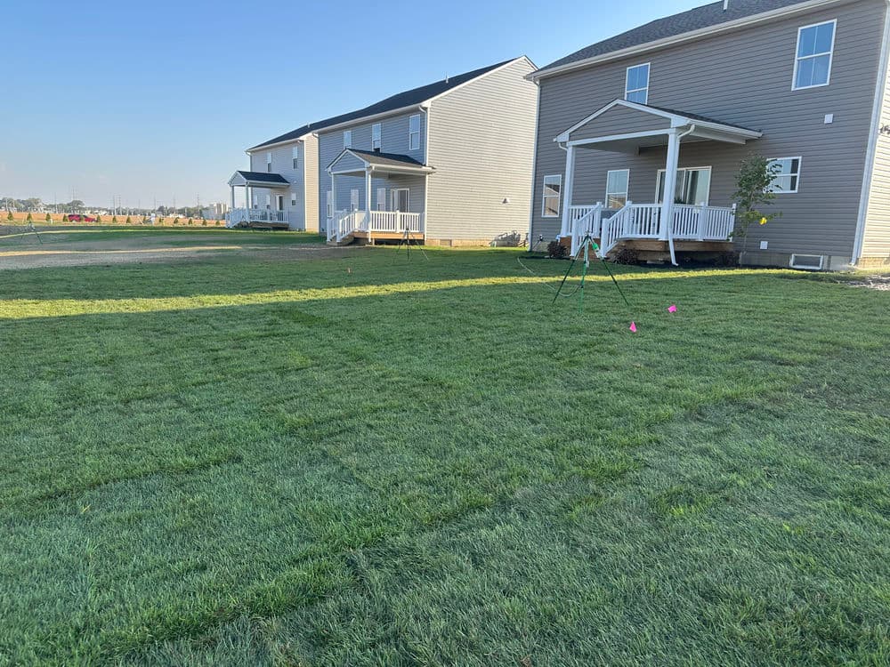Newly sodded lawn with two houses in the background and playground equipment.