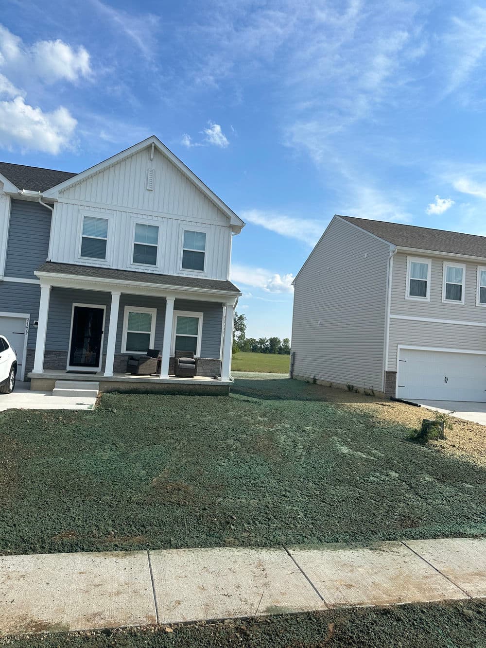 Newly built modern home with porch and landscaped yard in a suburban neighborhood.