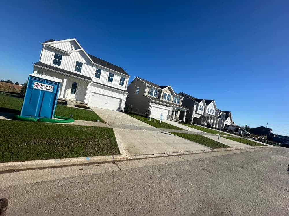 New residential homes lined along a suburban street with clear blue sky.