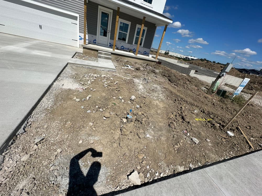Construction site with unfinished landscaping and gravel near a new house.