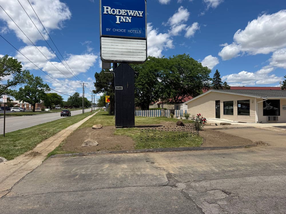 Rodeway Inn hotel sign with newly landscaped garden and clear blue sky.