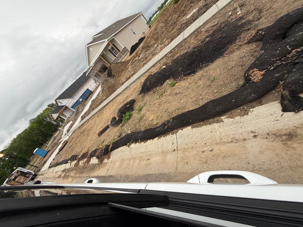 Construction site with new homes and erosion control fabric on a dirt lot.