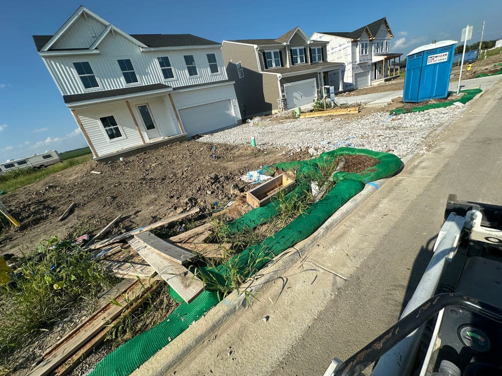 New residential construction site with two houses and a portable restroom on a sunny day.